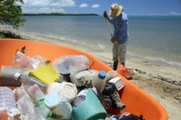 Man cleaning up a beach and recycling.