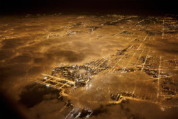 Lights of Chicago burn brightly at night under a blanket of clouds.