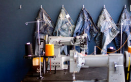 Jeans hanging up on a wall with sewing equipment.