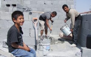 Men working at a construction sight with a child watching.