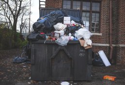 Dumpster with garbage overflowing and the street