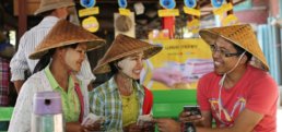 Men and women in Myanmar. using the Wave Money cellphone application for financial transactions.